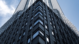A low angle shot of a tall city building with a blue sky in the background  in New York