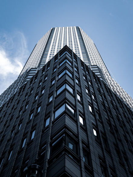 A low angle shot of a tall city building with a blue sky in the background in New York