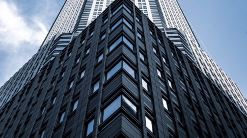 A low angle shot of a tall city building with a blue sky in the background in New York